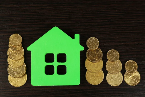 Model of house with coins on wooden table, closeup — Stock Photo, Image