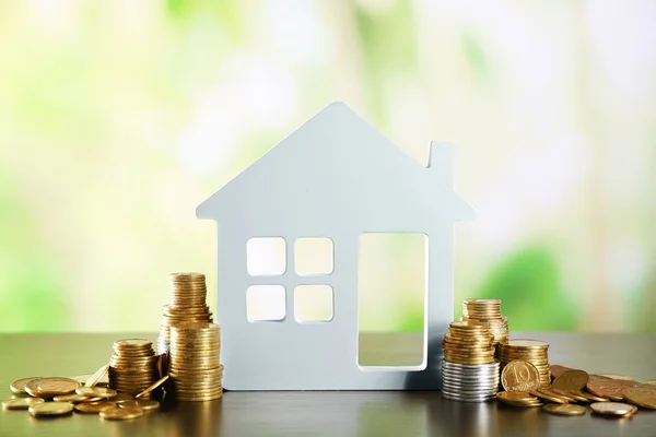 Modelo de casa con monedas sobre mesa de madera sobre fondo borroso — Foto de Stock