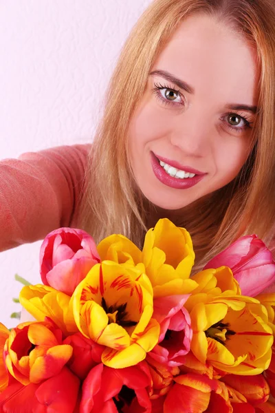 Portrait of young woman with beautiful bouquet of tulips on wallpaper background — Stock Photo, Image