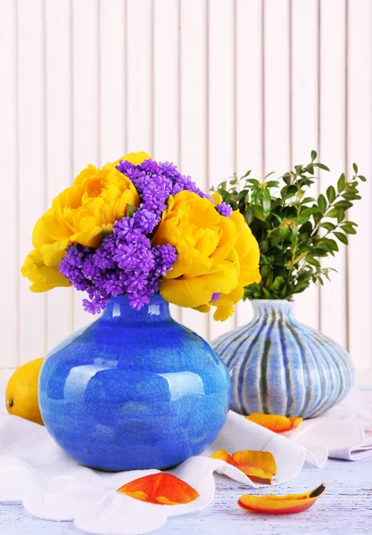 Composition with fresh spring flowers in ceramics vases on wooden background — Stock Photo, Image