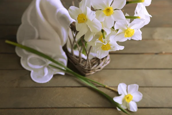 Fresh narcissus with wicker basket on wooden background — Stock Photo, Image