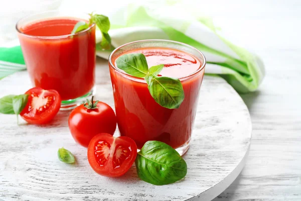 Szklanki soku świeżych pomidorów na drewnianym stole, zbliżenie — Zdjęcie stockowe