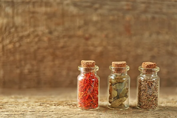 Sortimento de especiarias em garrafas de vidro em fundo de madeira — Fotografia de Stock