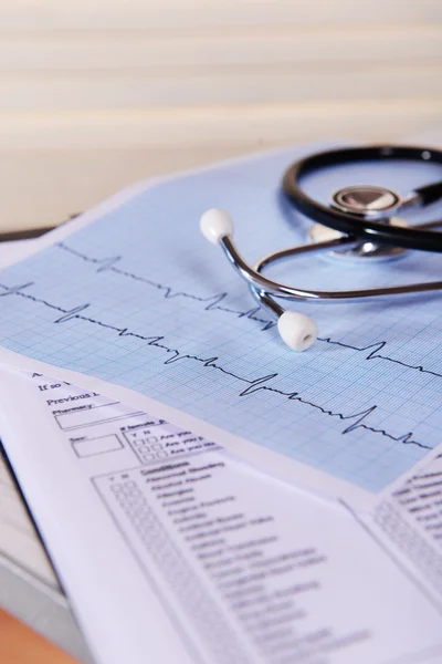 Kardiogram se stetoskopem na stole, detailní záběr — Stock fotografie