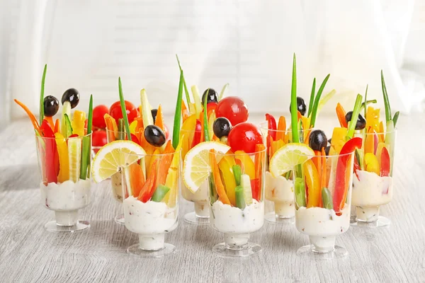 Snack von Gemüse in Gläsern auf Holztisch auf Vorhängen Hintergrund — Stockfoto