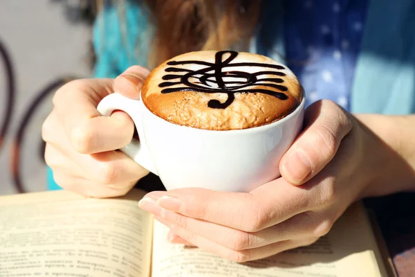 Cappuccino, hangjegy hab csésze tartó kezek — Stock Fotó