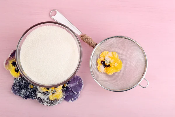 Candied sugared violet flowers, glass bowl with sugar,sieve on wooden background — Stock Photo, Image