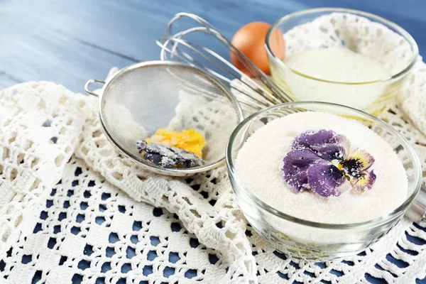 Herstellung von kandierten violetten Blüten mit Eiweiß und Zucker, auf farbigem Holzhintergrund — Stockfoto