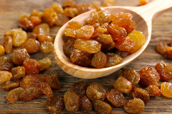 Raisins in spoon on wooden table, closeup — Stock Photo, Image