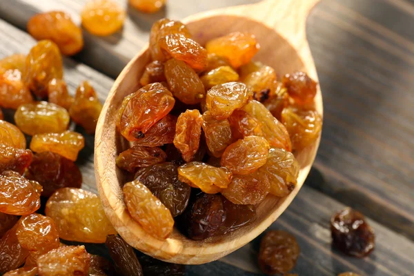 Raisins in spoon on wooden table, closeup — Stock Photo, Image