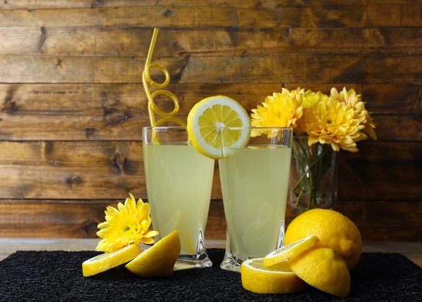 Bodegón con jugo de limón y limones en rodajas sobre fondo de madera —  Fotos de Stock