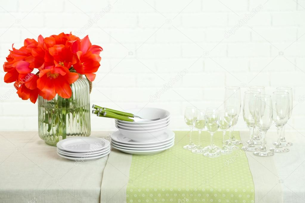 Table settings and tulip flowers in vase on table, on light background