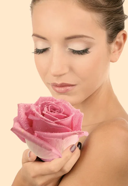 Bella giovane donna che tiene grande fiore rosa su sfondo beige — Foto Stock