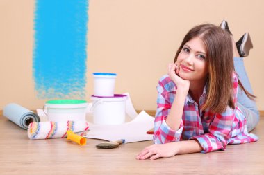 Güzel kız boyama duvar için ekipman ile yerde yatarken