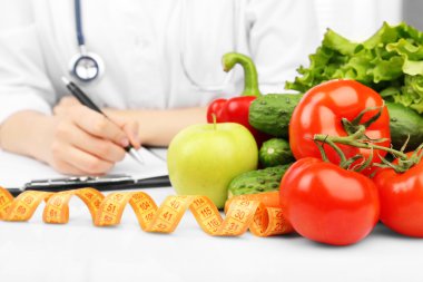 Nutritionist doctor writing  diet plan in office clipart