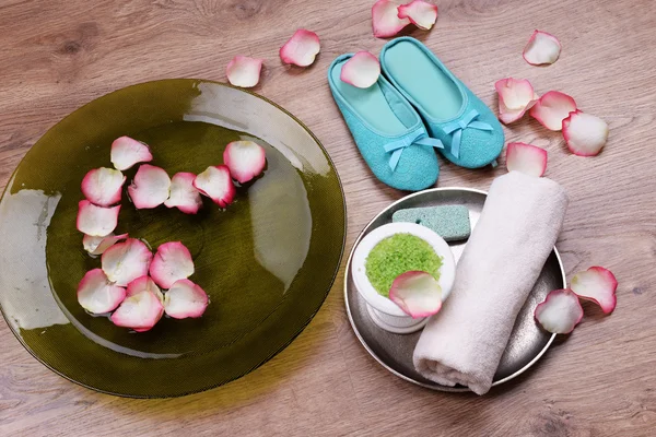 Spa bowl with water, rose petals, towel and slippers on light background. Concept of pedicure or natural spa treatment — Stock Photo, Image