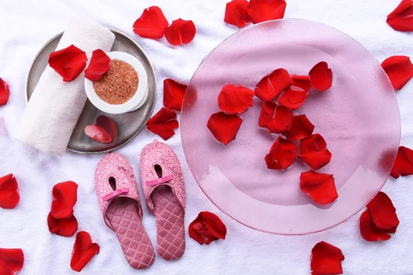 Wellnessschale mit Wasser, Rosenblättern, Handtuch und Hausschuhen auf hellem Hintergrund. Konzept der Pediküre oder natürlichen Wellness-Behandlung — Stockfoto