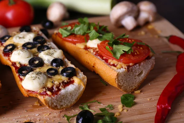 Different sandwiches with vegetables and cheese on cutting board on table close up — Stock Photo, Image