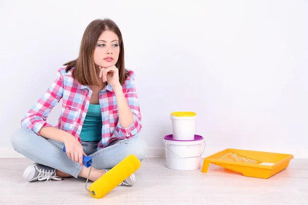 Mooi meisje, zittend op de vloer met apparatuur voor schilderij muur — Stockfoto