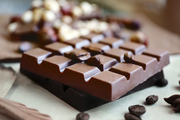 Chocolate con granos de café sobre papel, primer plano —  Fotos de Stock