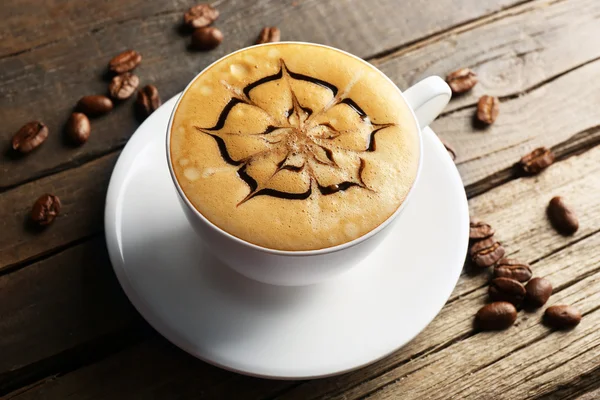 Šálek kávy latte umění s zrna na dřevěné pozadí — Stock fotografie