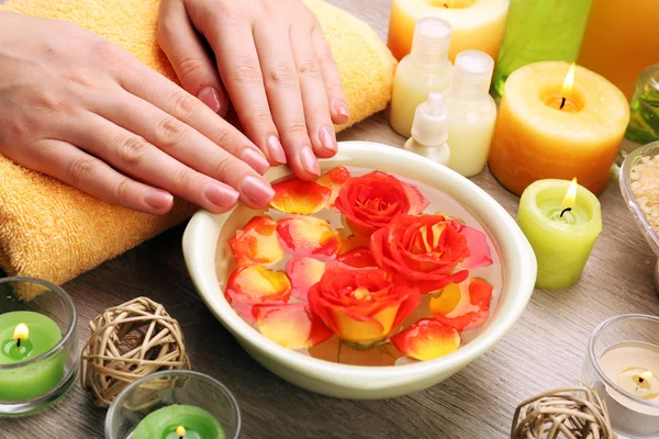 Vrouwelijke handen met kom aroma spa water op houten tafel, close-up — Stockfoto