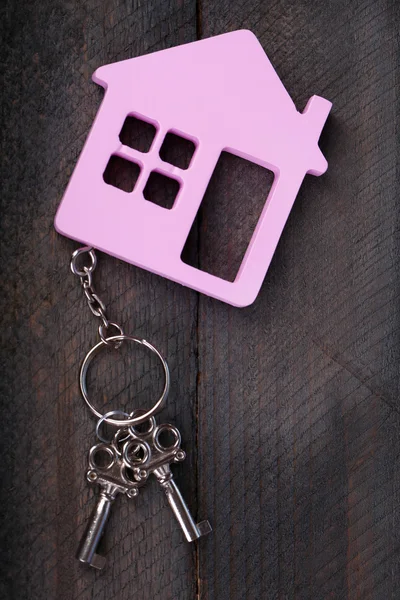 Toy house with key on wooden background — Stock Photo, Image