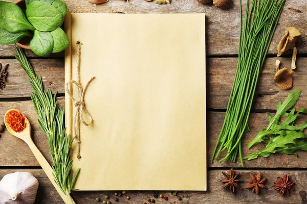 Libro de recetas abierto con hierbas frescas y especias sobre fondo de madera — Foto de Stock