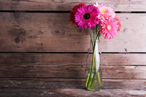 Schöne helle Gerbera-Blüten in Glasvase auf Holzgrund — Stockfoto