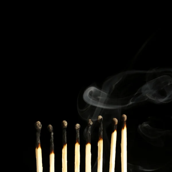 Burned matches in smoke on black background — Stock Photo, Image