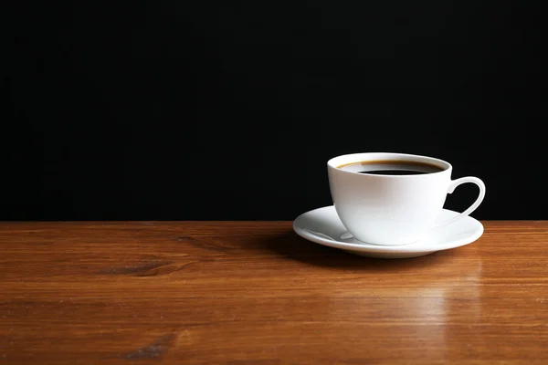 Taza de café sobre la mesa sobre fondo oscuro —  Fotos de Stock