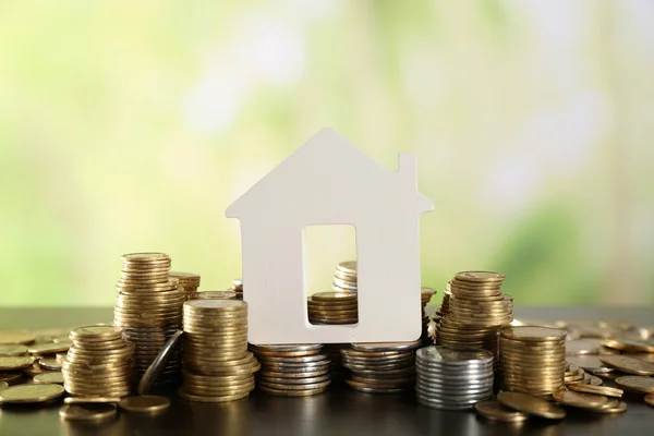 Modelo de casa con monedas sobre mesa de madera sobre fondo borroso — Foto de Stock