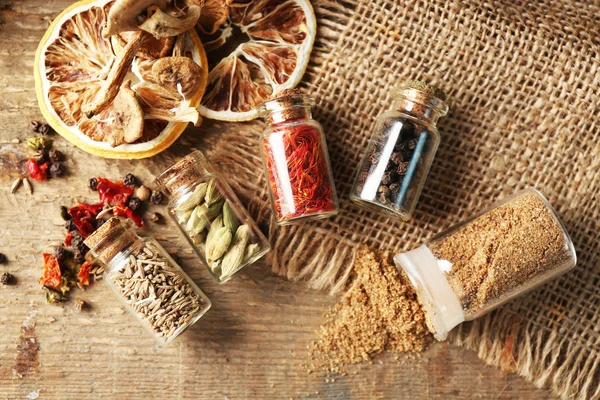 Assortment of spices in glass bottles on wooden background — Stock Photo, Image