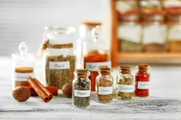 Assortment of spices in glass bottles on wooden background — Stock Photo, Image