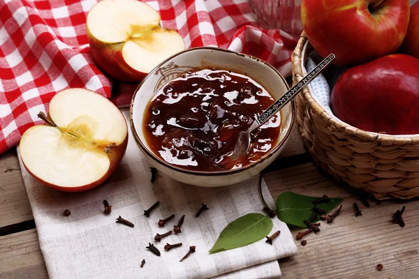 Apple jam and fresh red apples on wooden table close-up