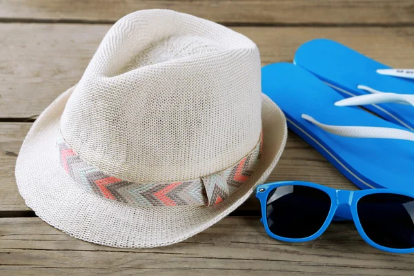 Gafas de sol, chanclas y sombrero fondo de madera — Foto de Stock