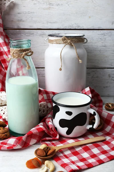 Leche en cristalería con nueces y galletas en mesa de madera con servilleta, primer plano — Foto de Stock