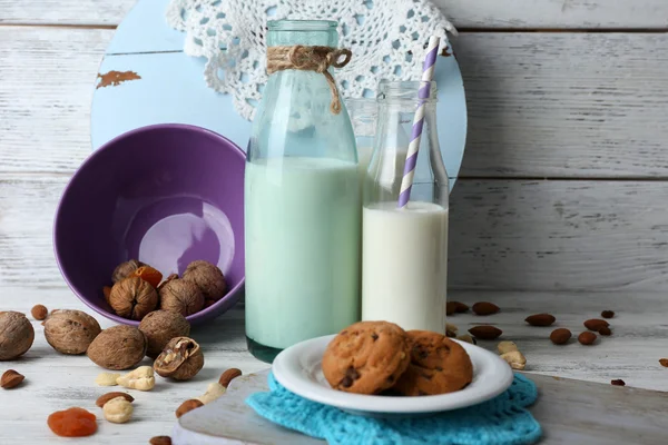 Susu dalam gelas dengan kenari dan kue di latar belakang — Stok Foto