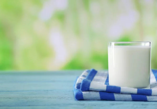 Szklanka mleka na drewnianym stole, na tle zieleni — Zdjęcie stockowe