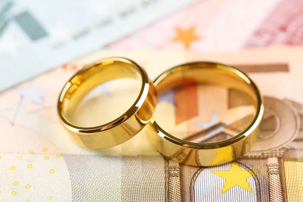 Golden wedding rings on banknotes background. Marriage of convenience — Stock Photo, Image