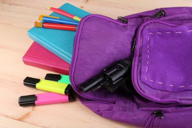 Ahşap arka plan üzerinde okul sırt çantası silah