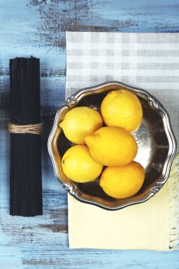Peynir, siyah spagetti ve ahşap masa üstüne limon görüntüleyin