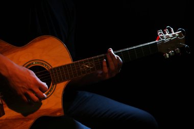 Genç adam akustik gitarla çalıyor.