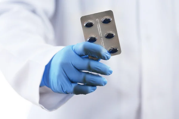 Plaat van pillen in arts hand op witte achtergrond — Stockfoto
