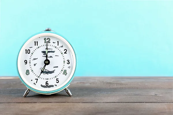 Alarm clock on wooden table on blue background — Stock Photo, Image