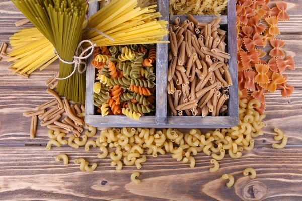 Diversi tipi di pasta in scatola su sfondo di legno — Foto Stock