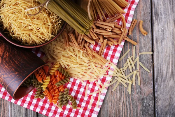 Different types of pasta on napkin on wooden background — Stock Photo, Image