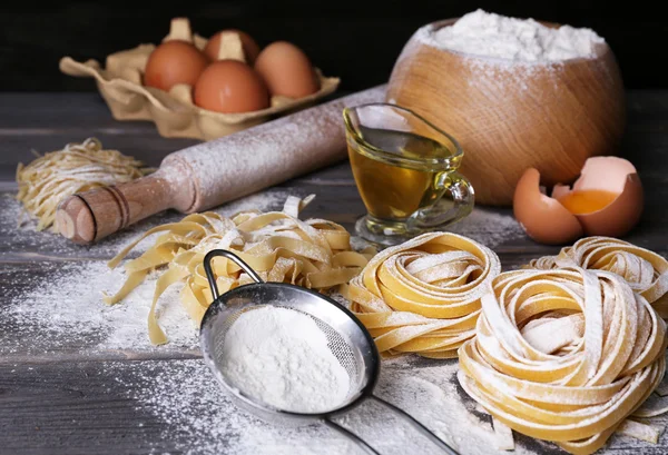 Сирі домашні макарони та інгредієнти для макаронних виробів на дерев'яному фоні — стокове фото
