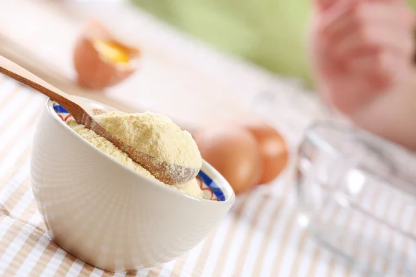 Cornmeal in bowl with wooden spoon on table close up — Stock Photo, Image