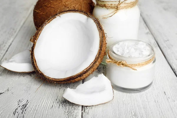 Huile de coco fraîche en verrerie sur fond de table en bois de couleur — Photo